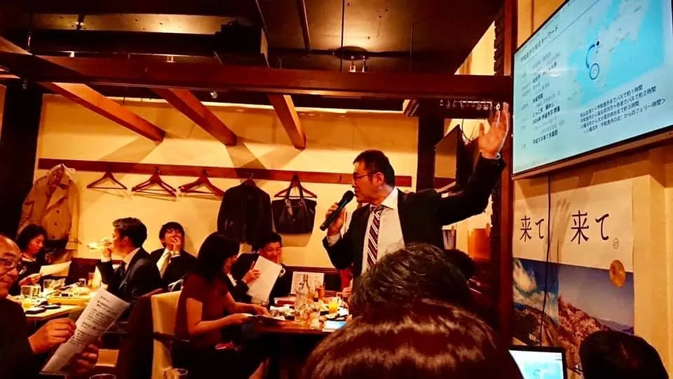 店内でマイクを持って話す人と参加者