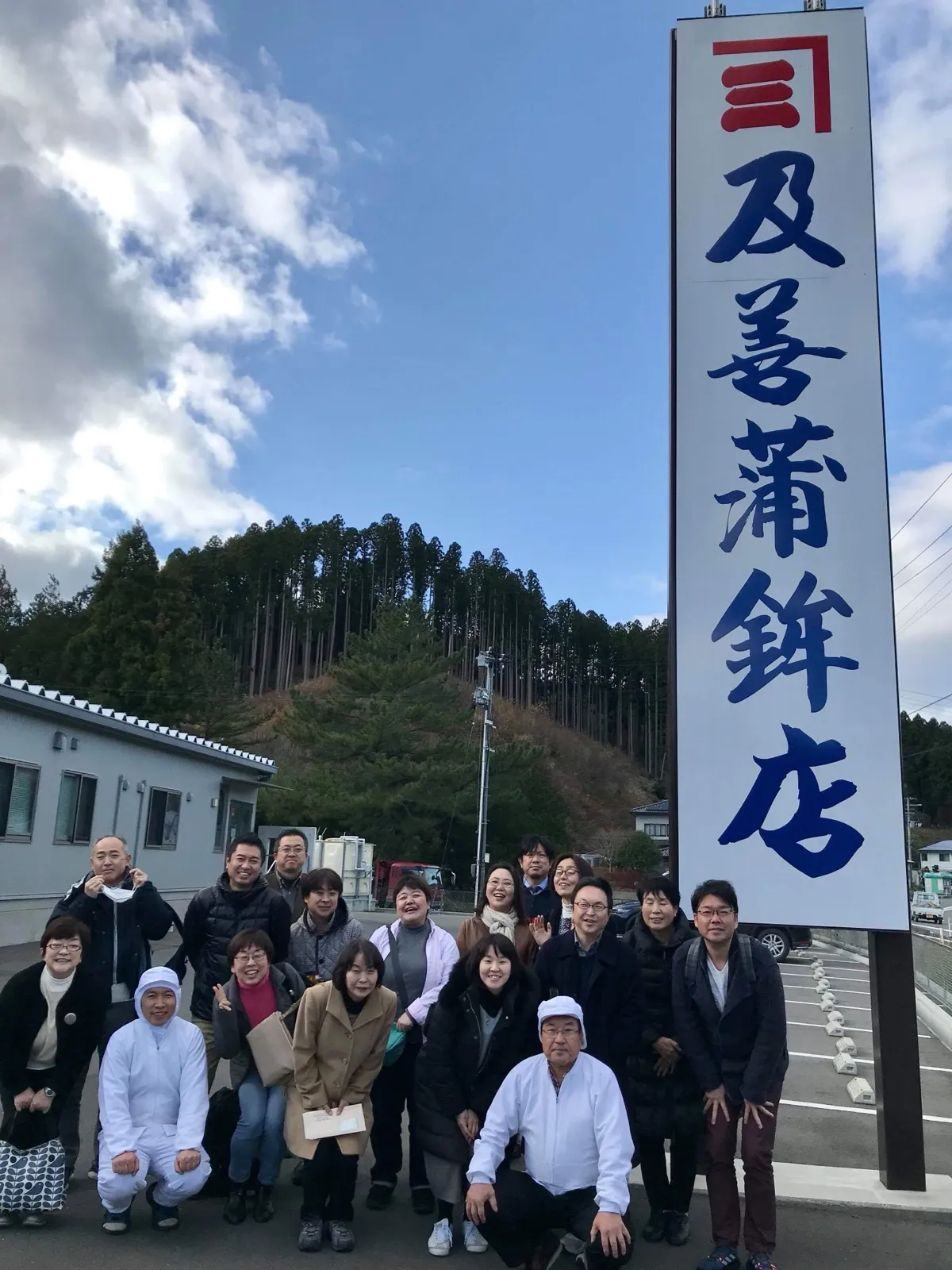 青空と看板の前の集合写真